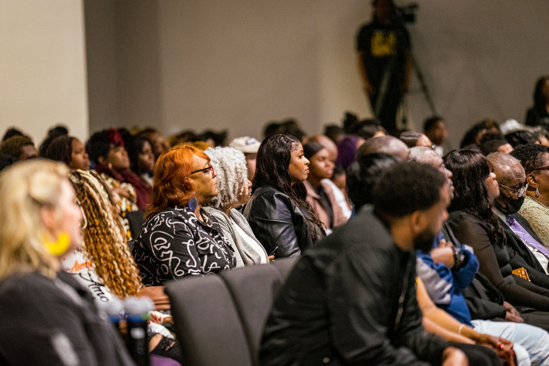 A large group of people are sitting in chairs in a room.