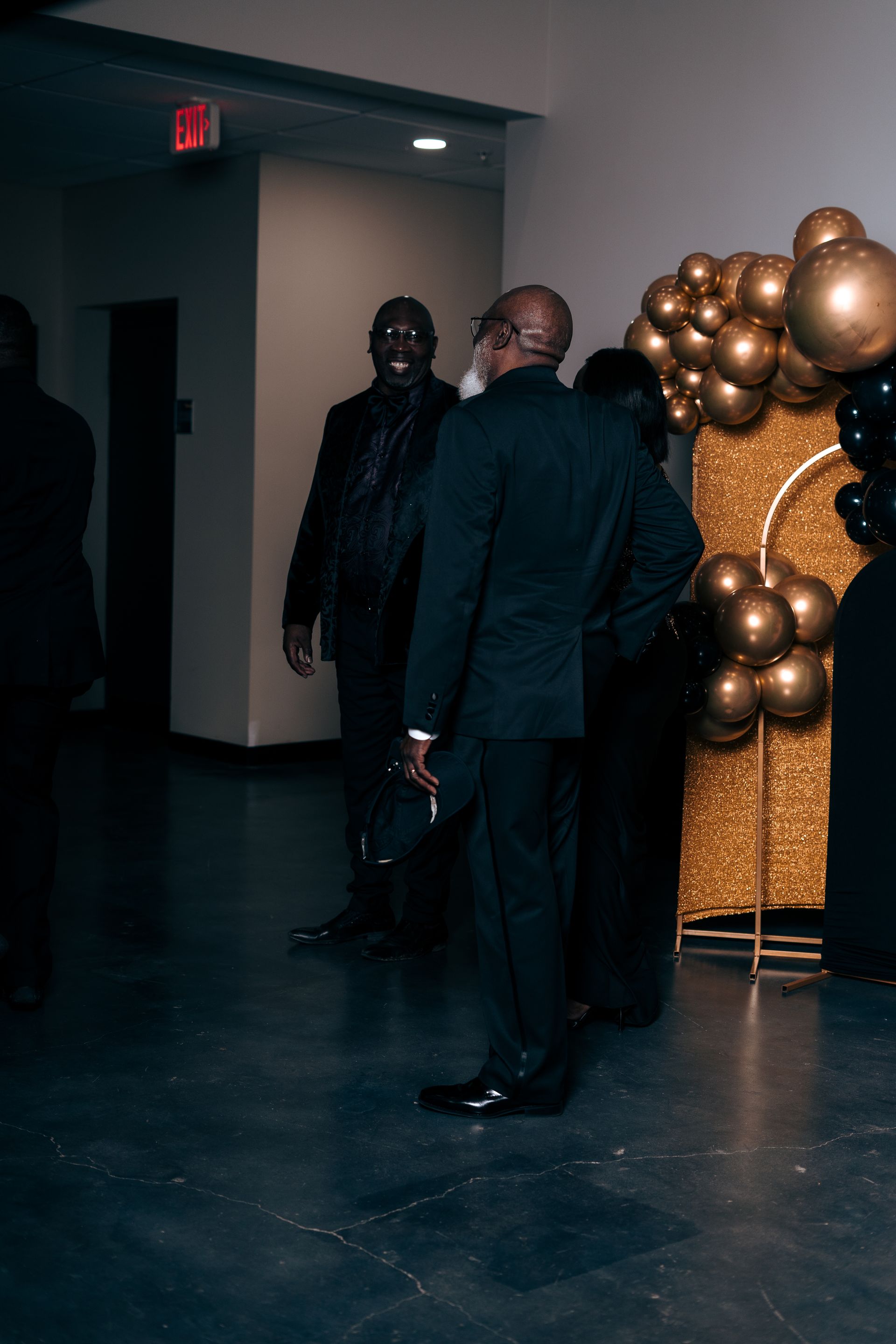 A group of men in suits are standing in a dark room.