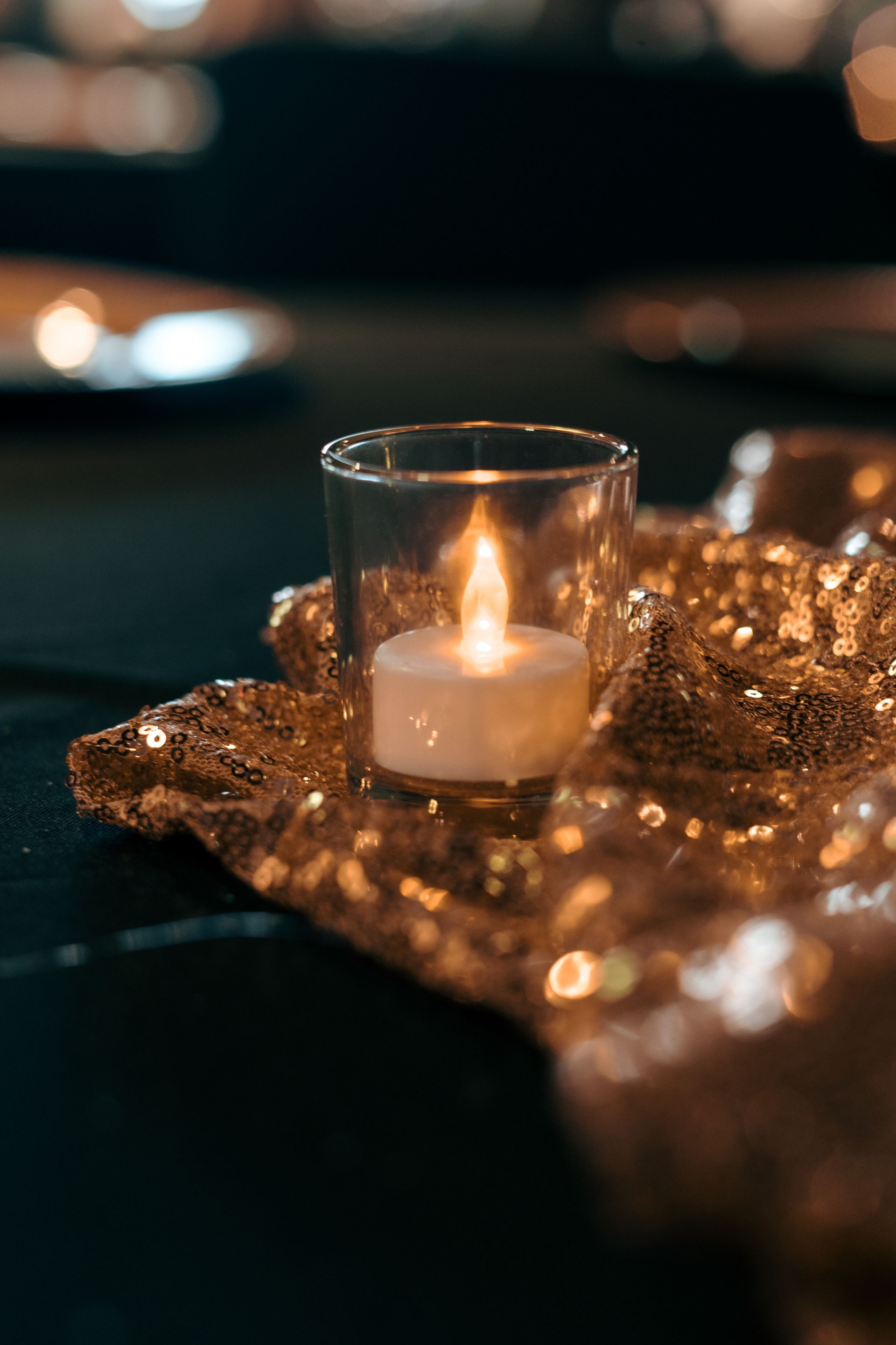 A lit candle in a glass on a table.