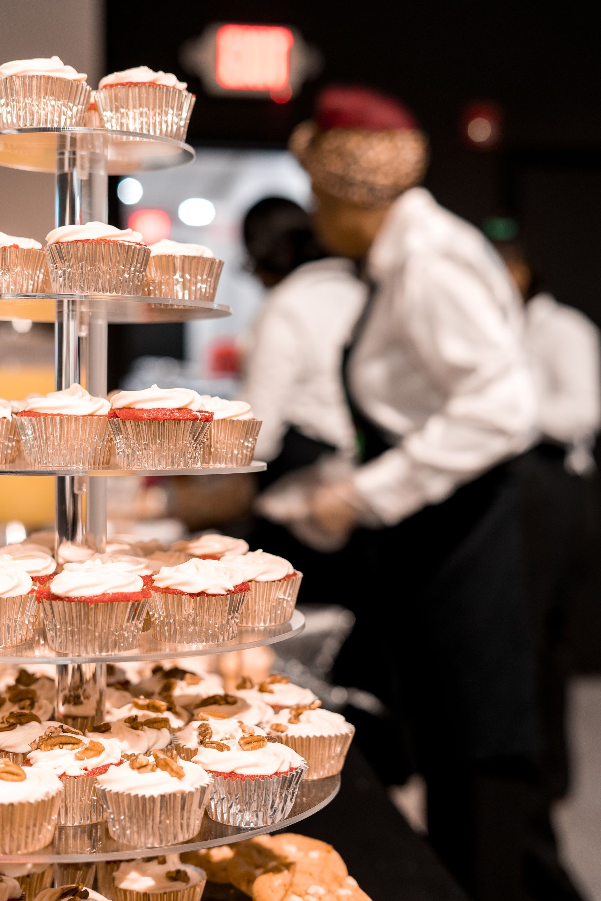 A display of cupcakes on a table with a man in the background.