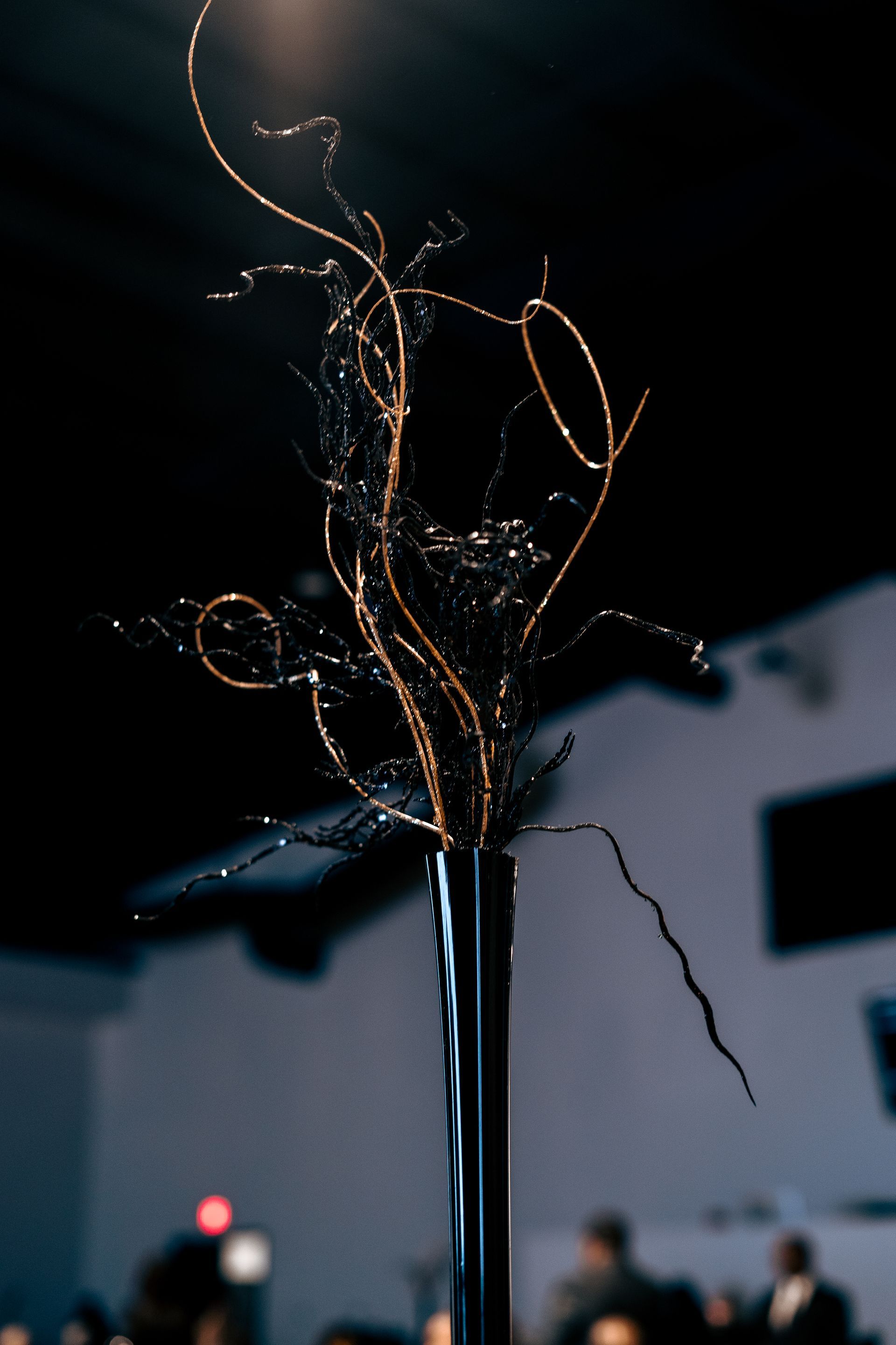 A tall black vase filled with branches and flowers