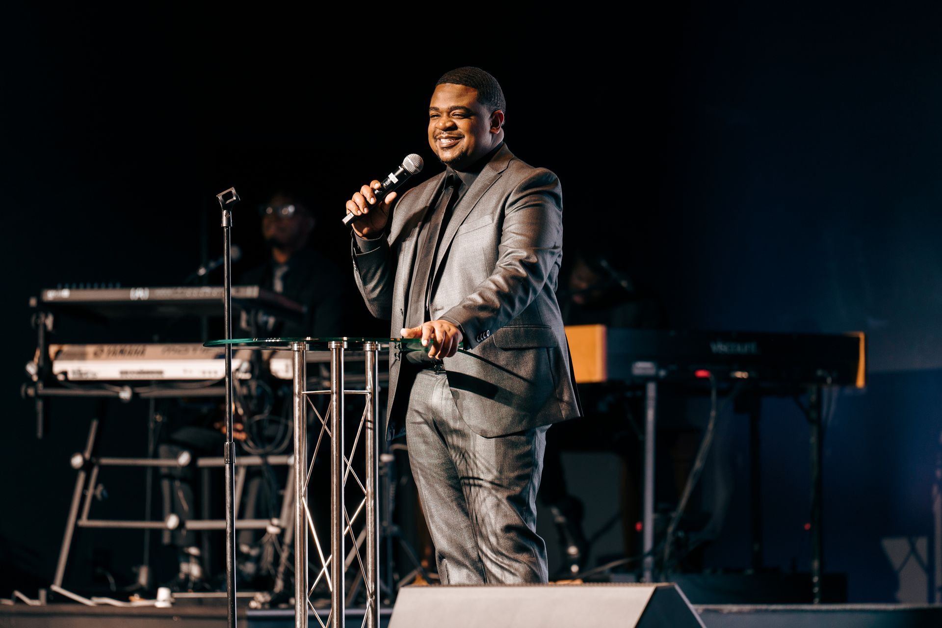 A man in a suit is standing on a stage holding a microphone.