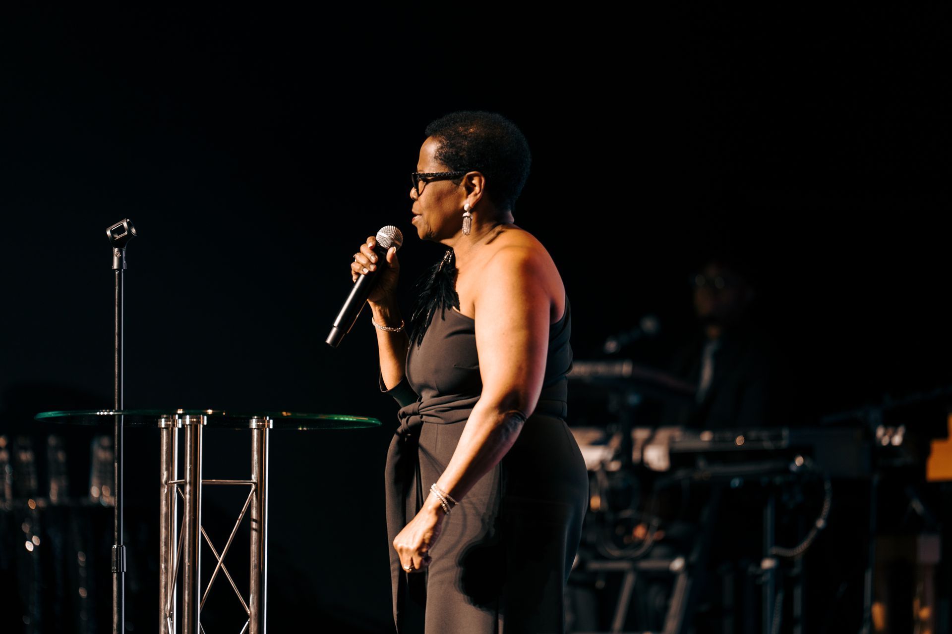 A woman is singing into a microphone on a stage.