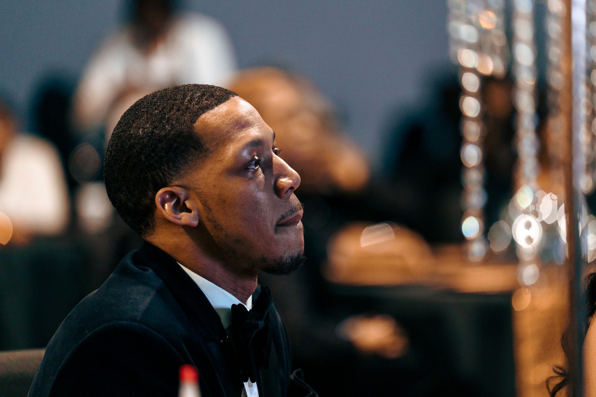 A man in a tuxedo is sitting in a chair and looking up.