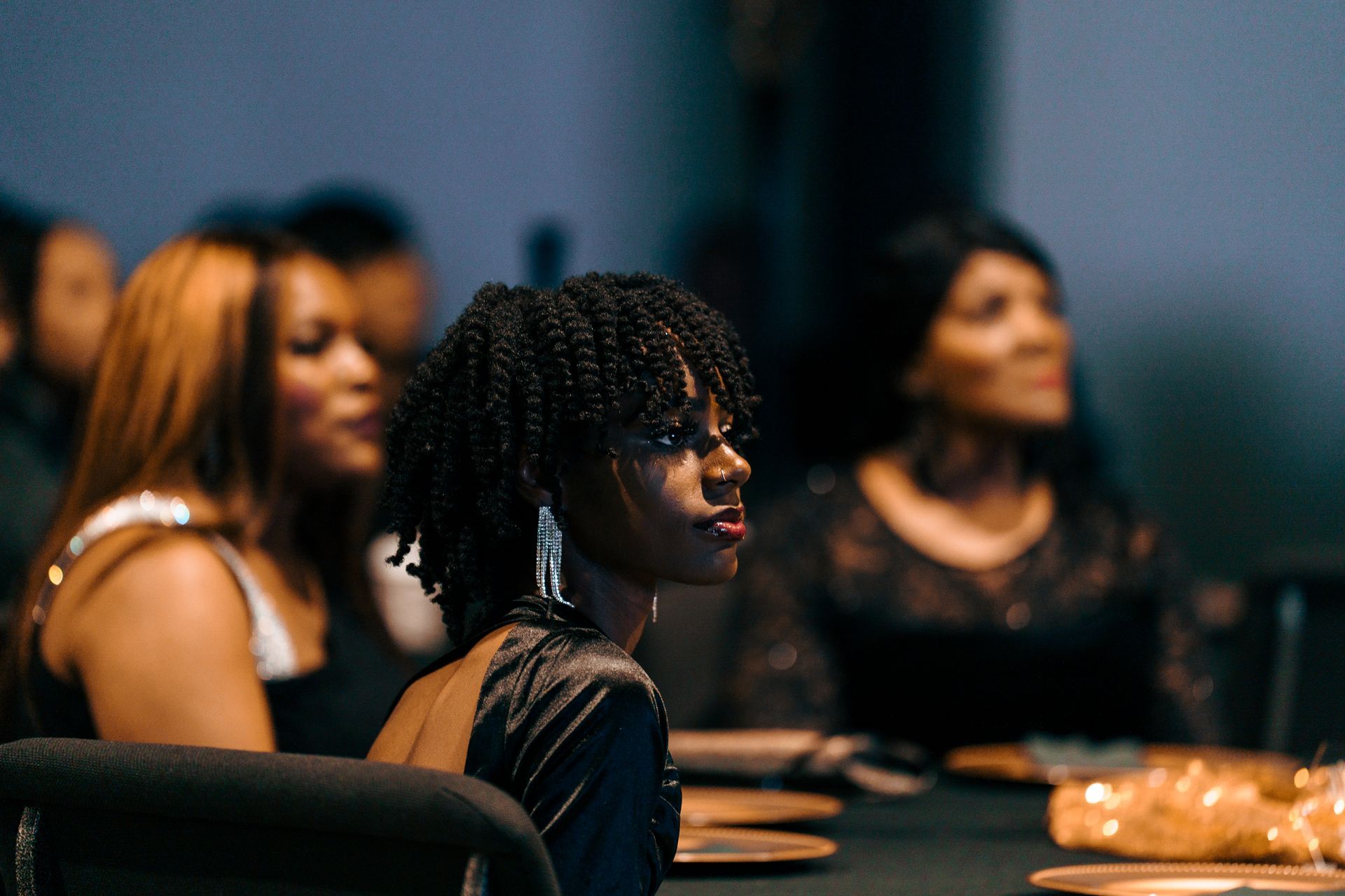 A group of women are sitting at a table in a dark room.