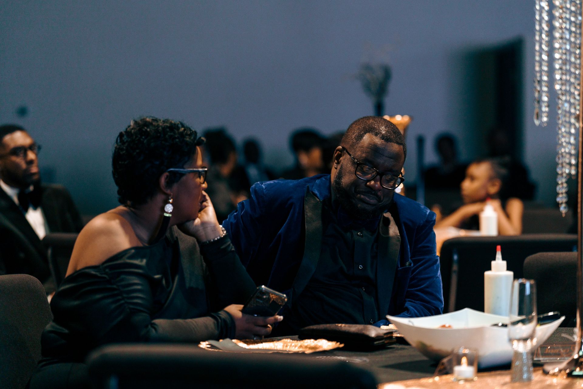 A man and a woman are sitting at a table at a party.