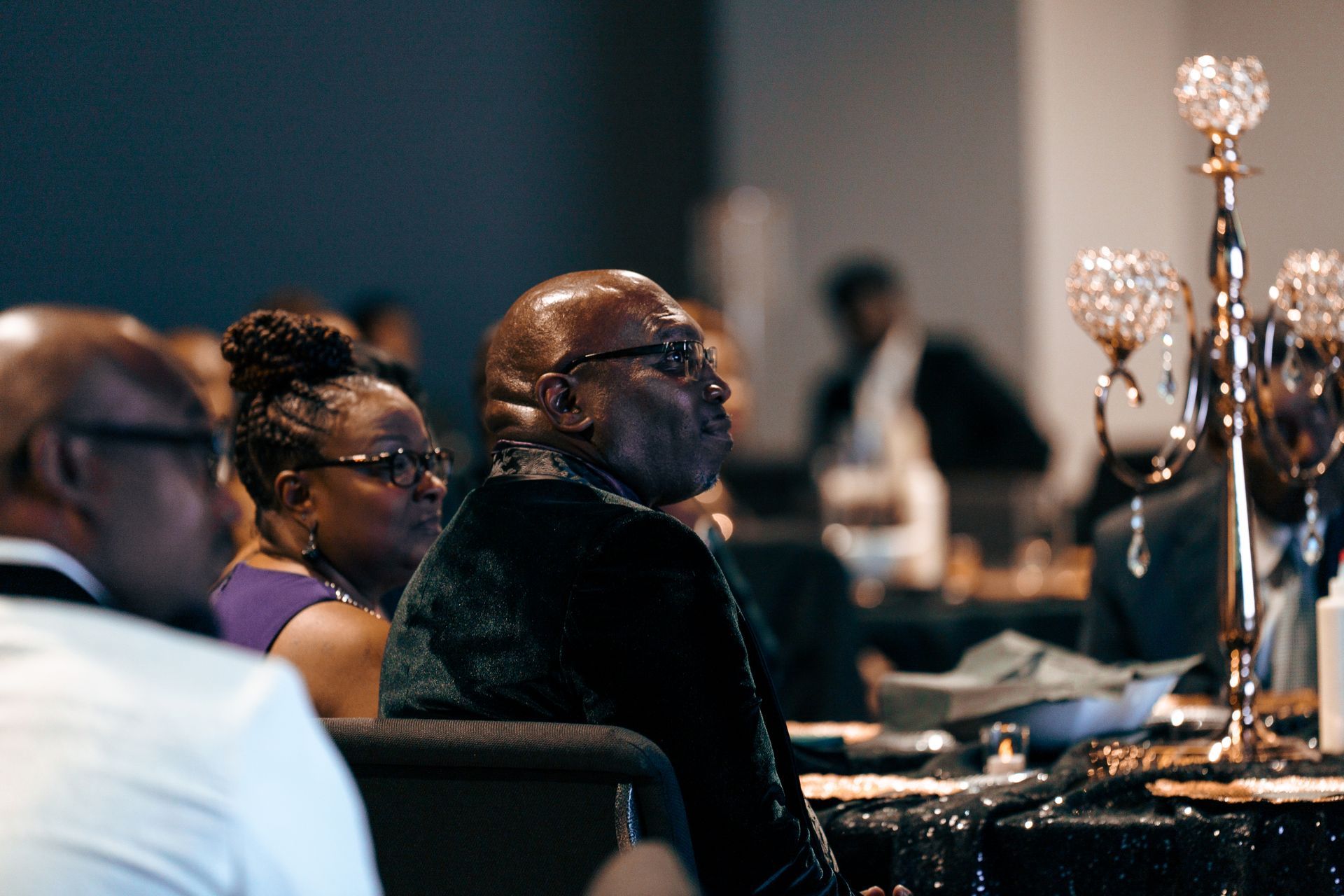 A group of people are sitting at a table with candles on it.