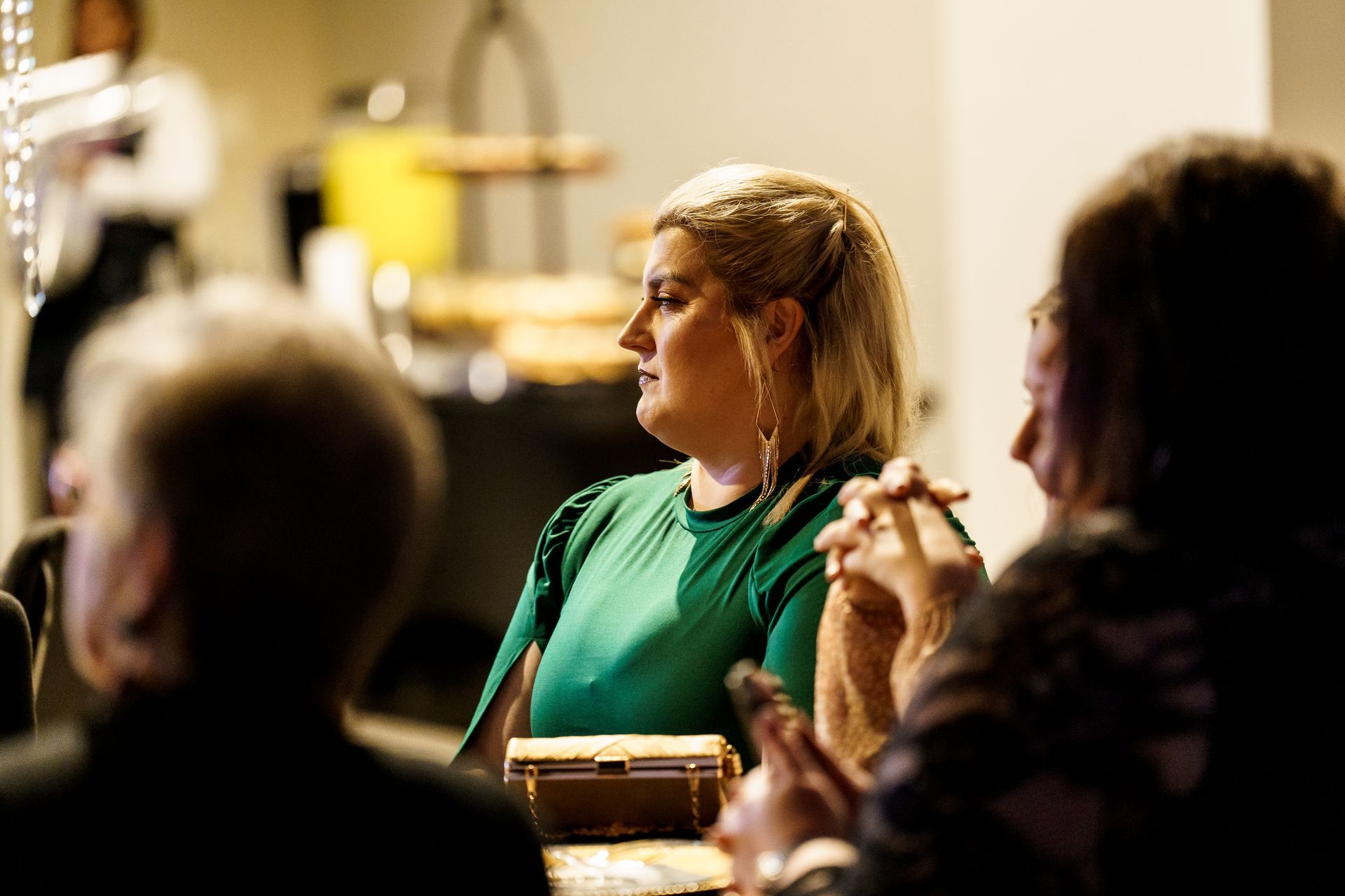 A woman in a green shirt is sitting at a table with other people.