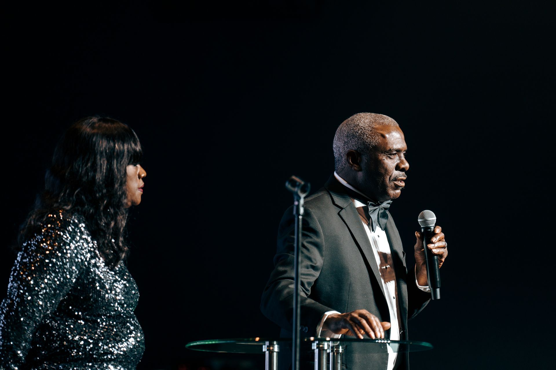 A man and a woman are singing into microphones on a stage.