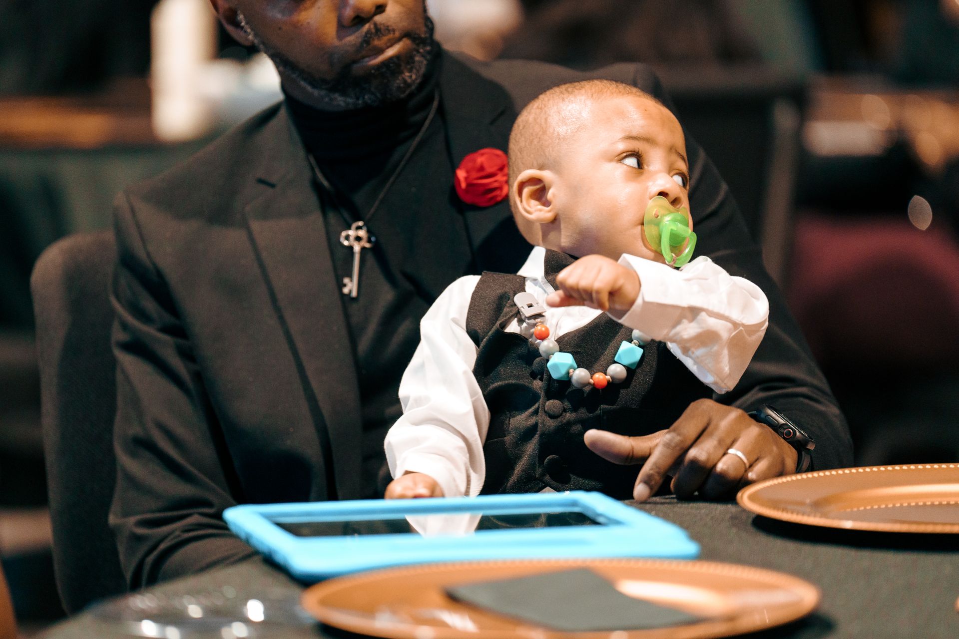 A man is holding a baby in his arms while sitting at a table.