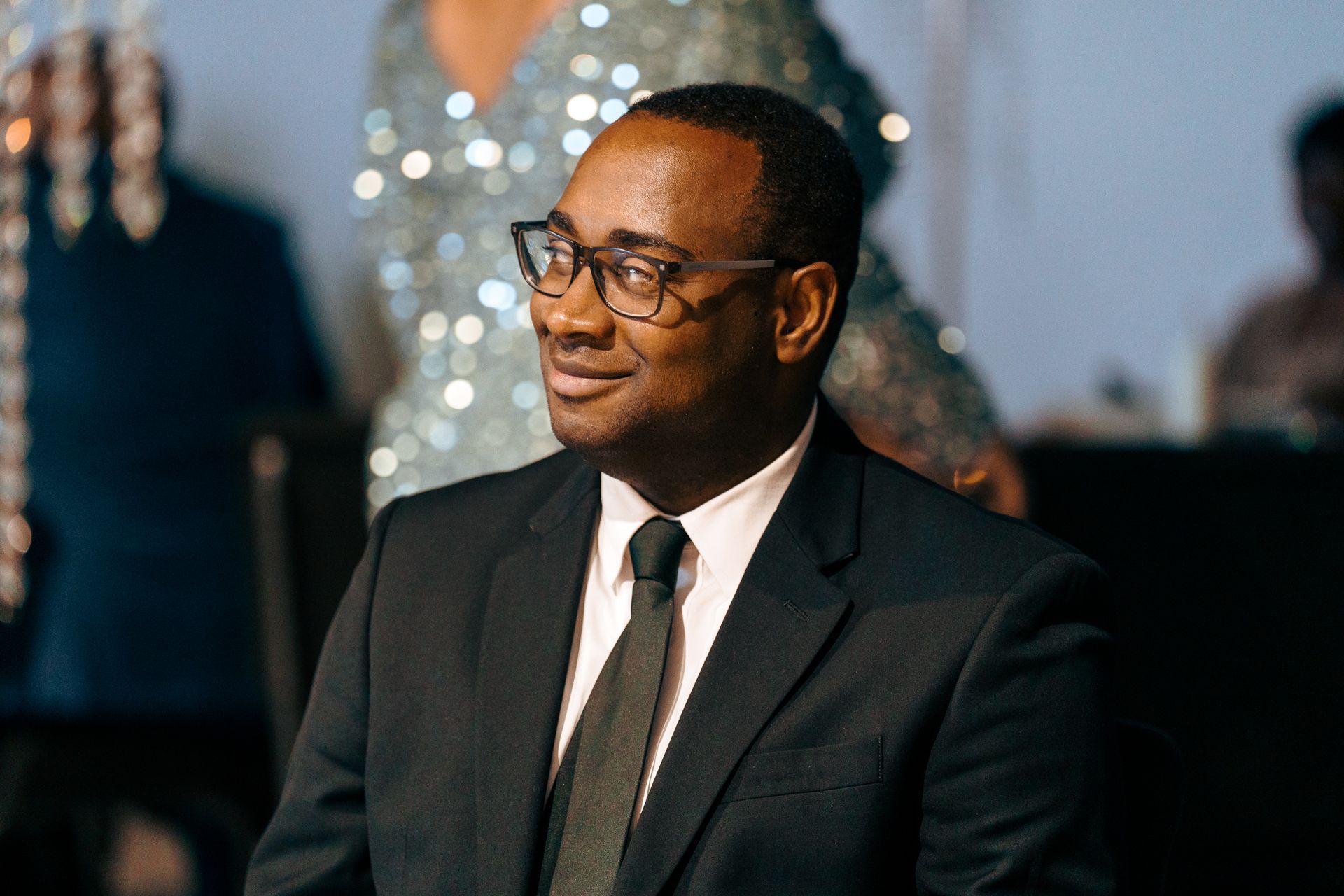 A man in a suit and tie is sitting down and smiling.