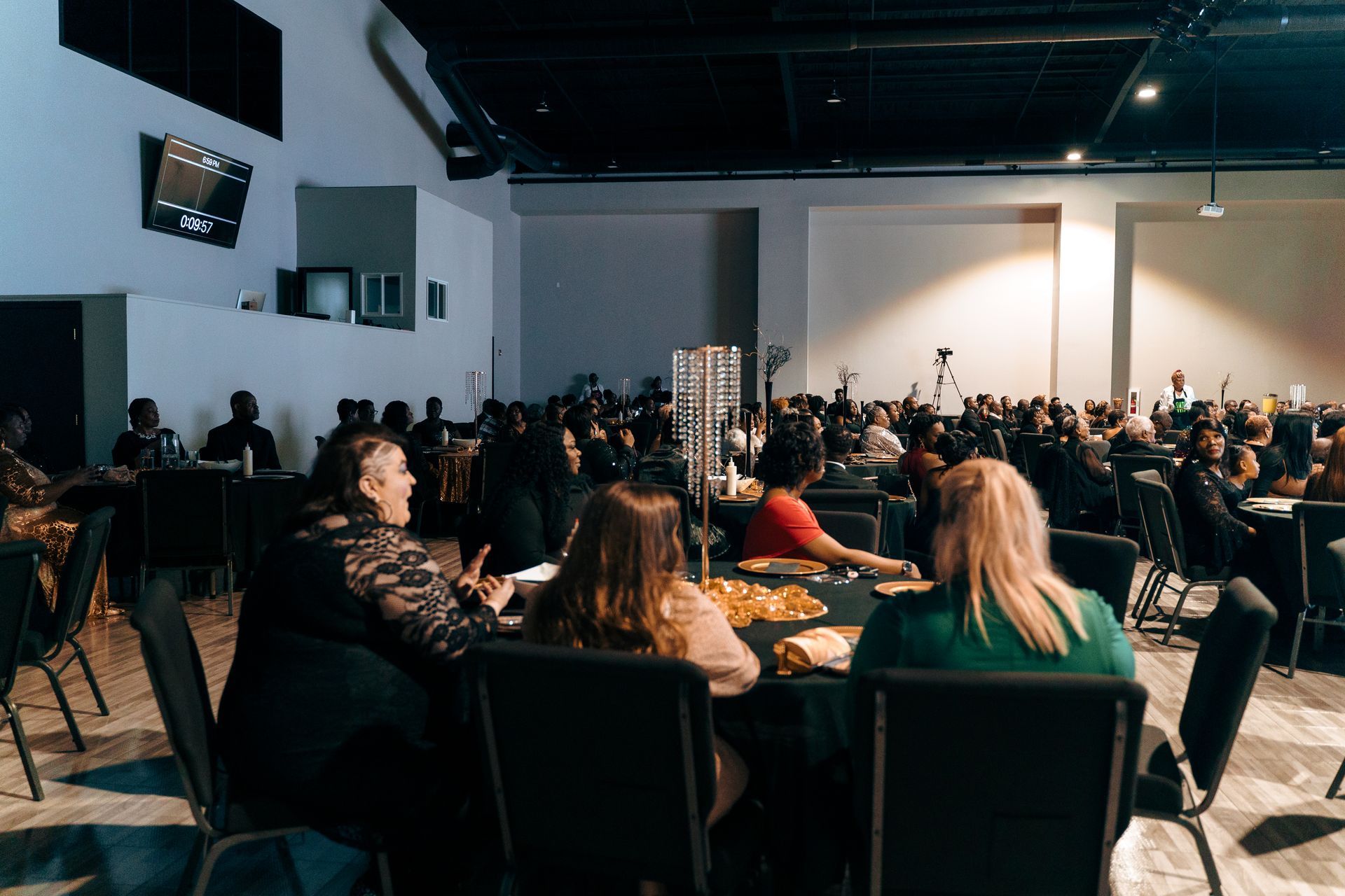 A large group of people are sitting at tables in a large room.