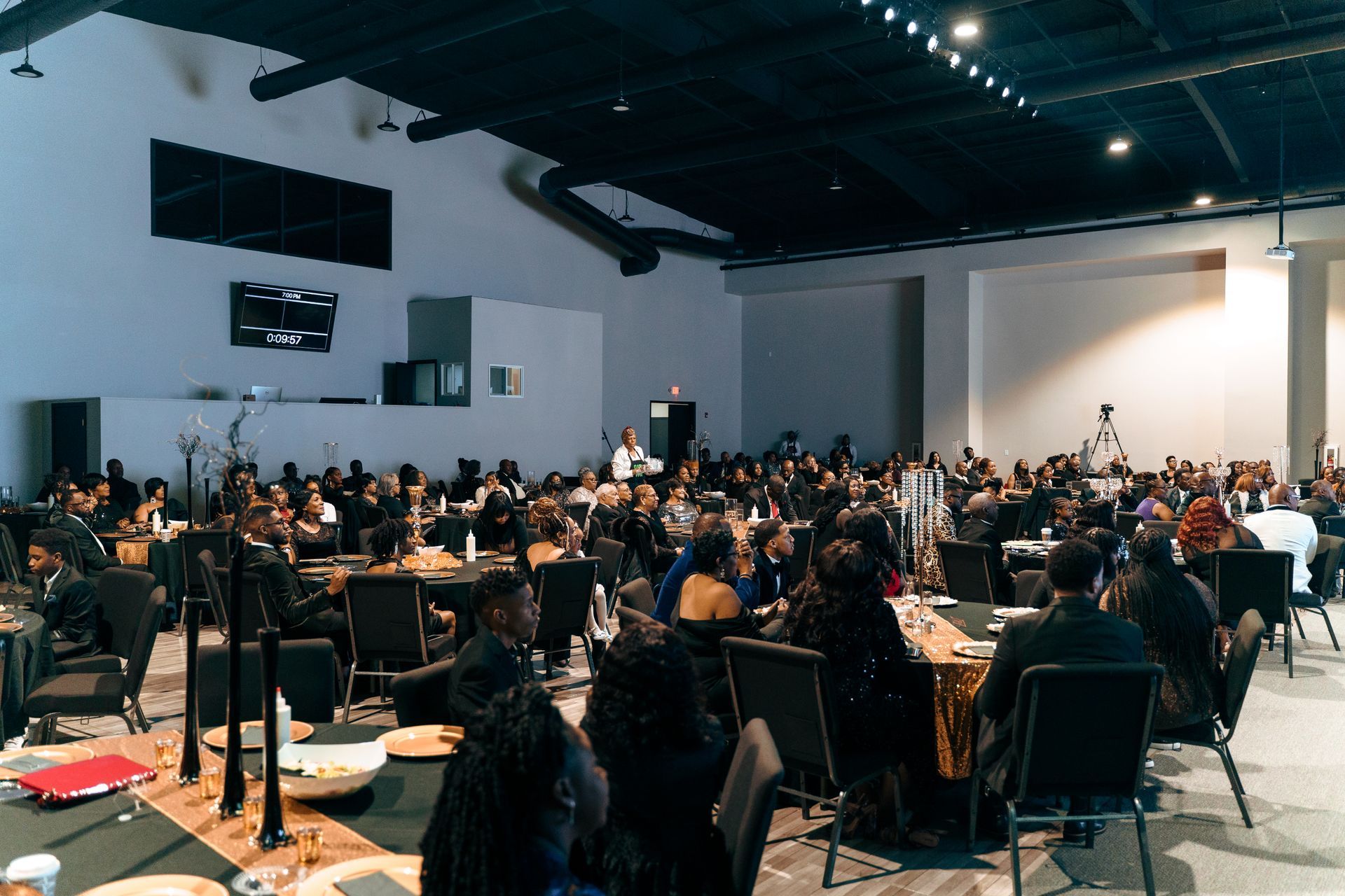 A large group of people are sitting at tables in a large room.