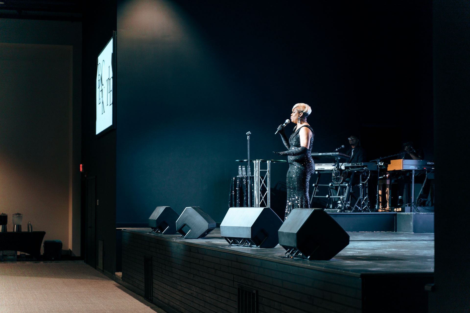 A woman is singing into a microphone on a stage.