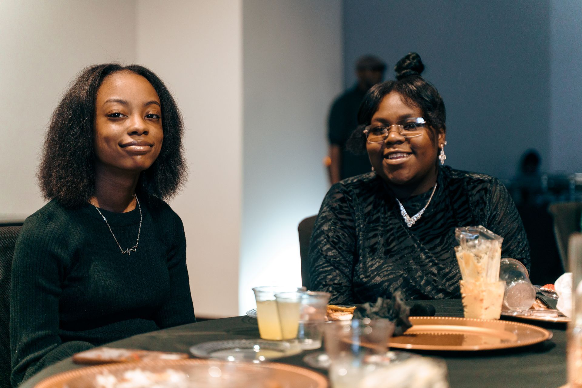 Two women are sitting at a table with drinks.