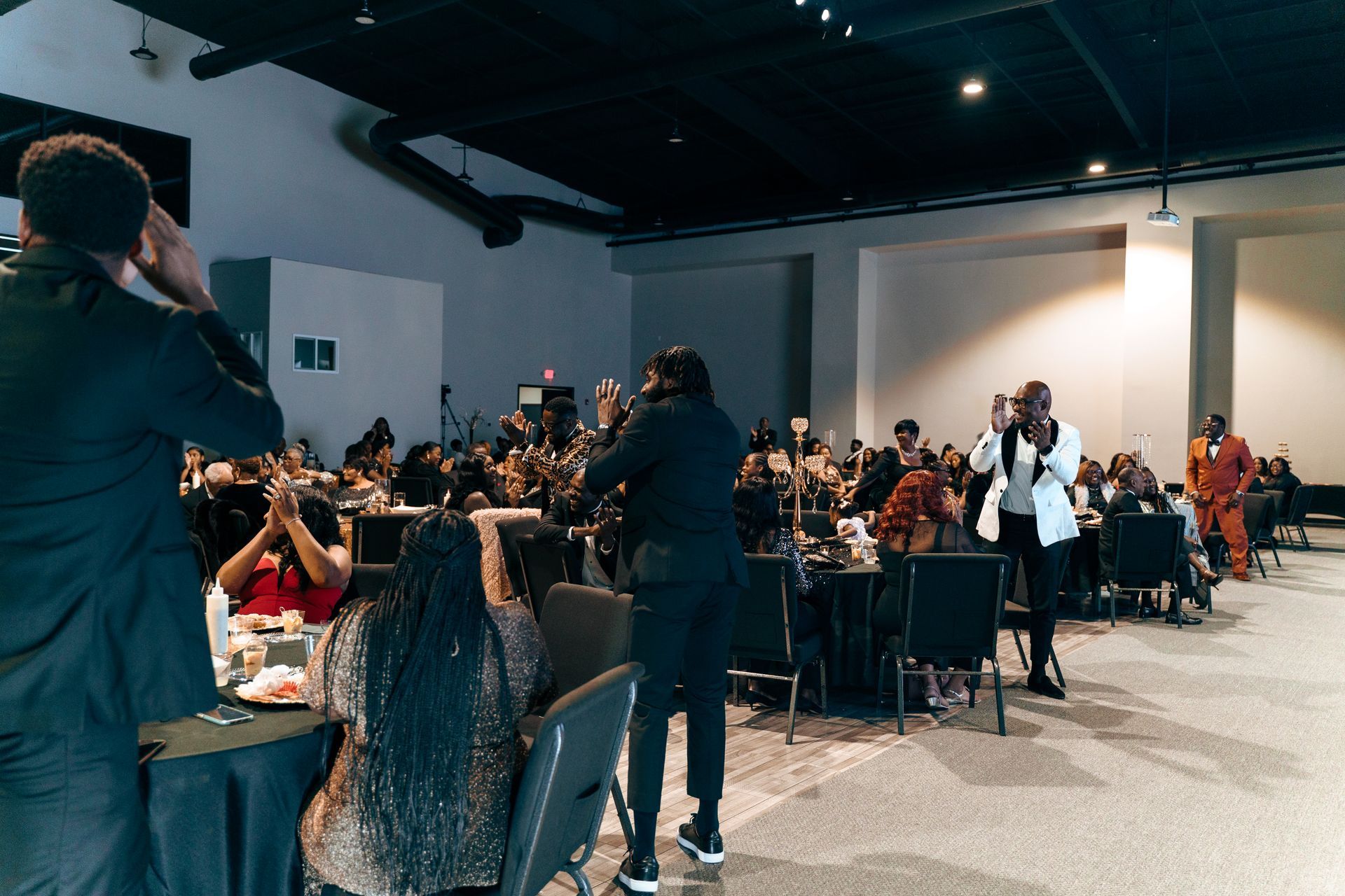 A group of people are sitting at tables in a large room.