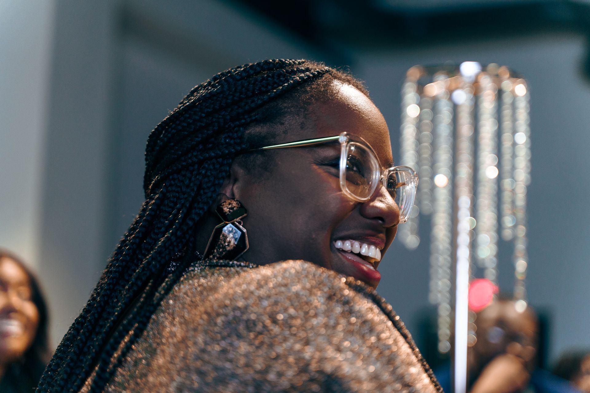 A woman wearing glasses is smiling and looking over her shoulder.