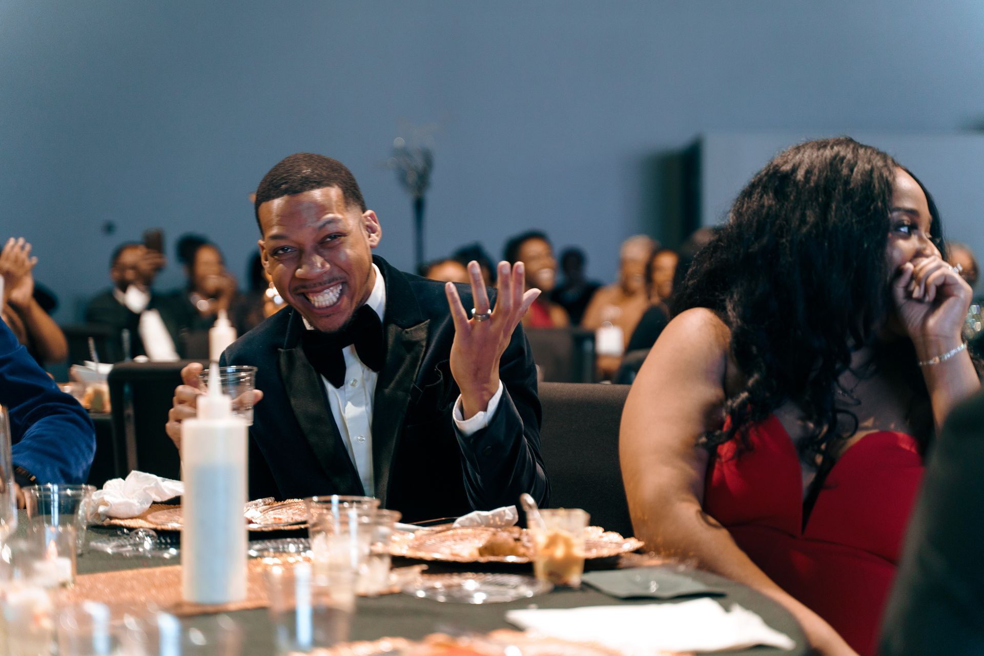 A man in a tuxedo is sitting at a table with a woman in a red dress.