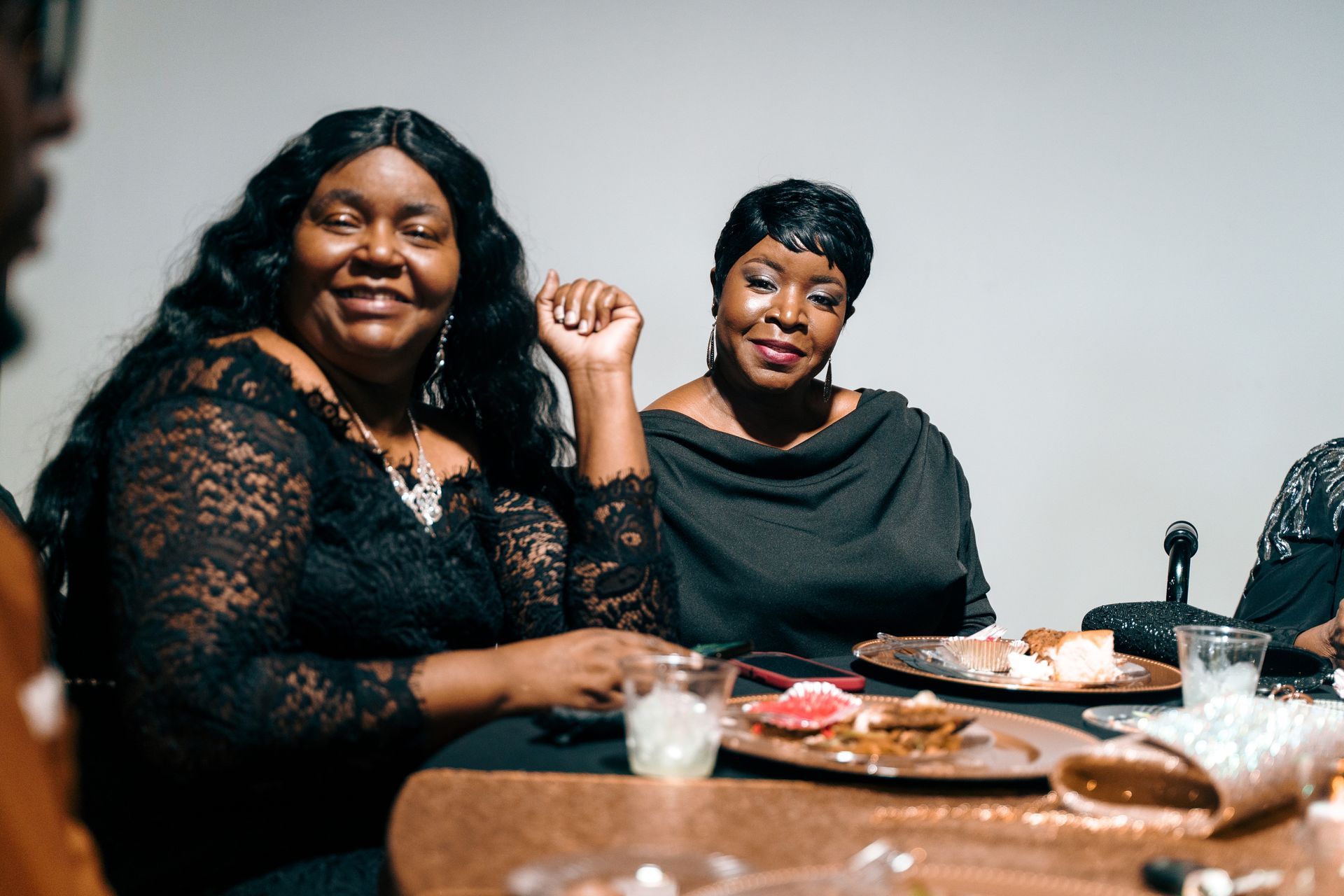 Two women are sitting at a table with plates of food.