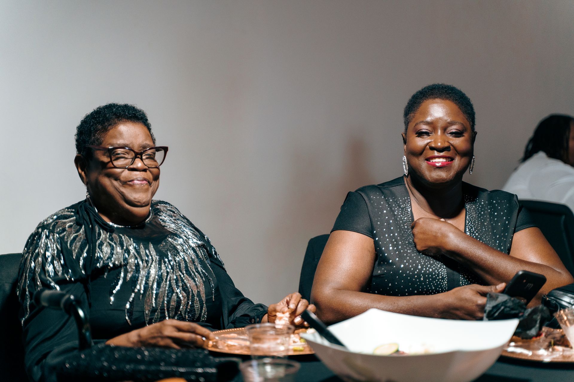 Two women are sitting at a table with a bowl of food.