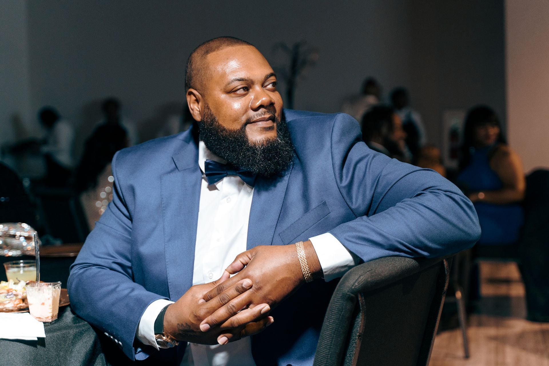 A man in a suit and bow tie is sitting in a chair.