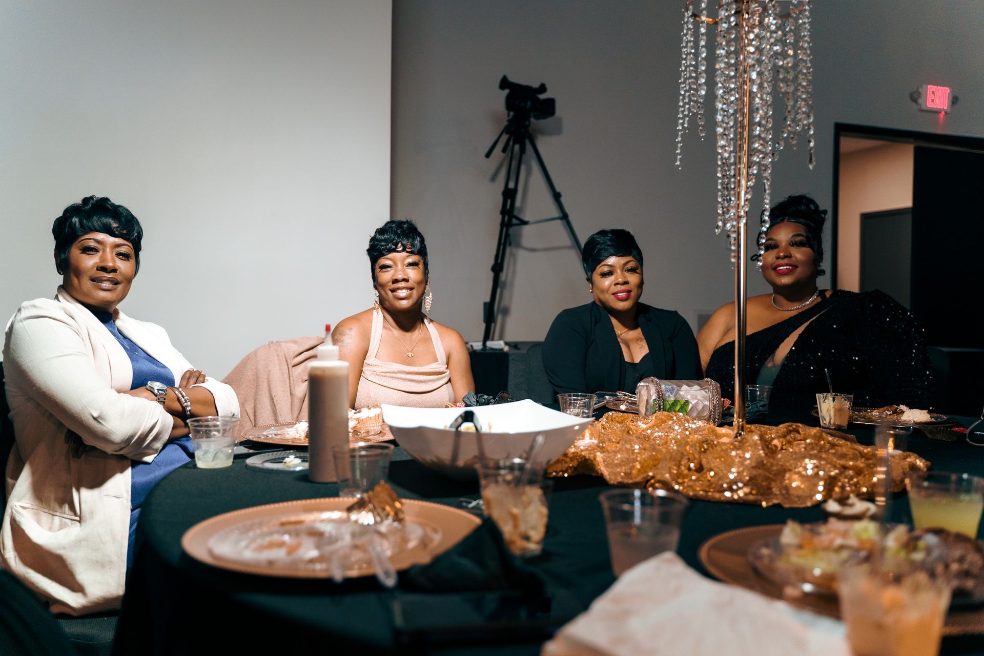A group of women are sitting at a table with plates and glasses.