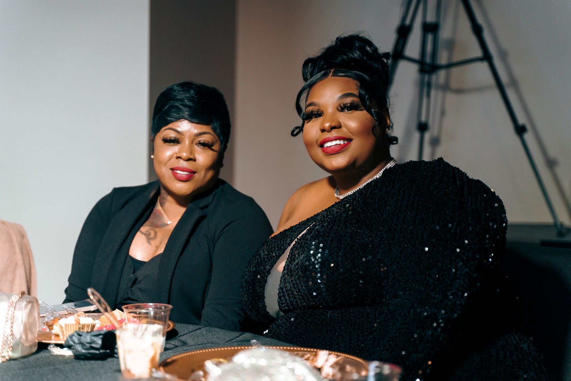 Two women are sitting at a table and smiling for the camera.