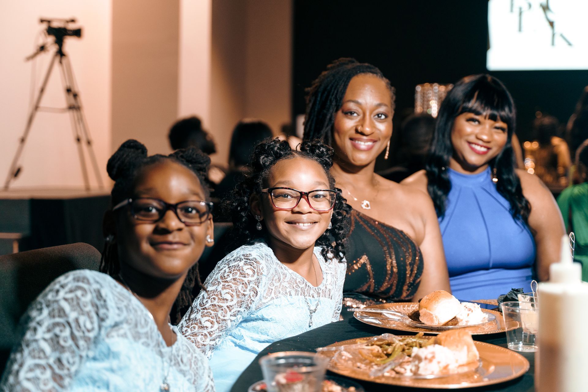 A group of women are sitting at a table with plates of food.