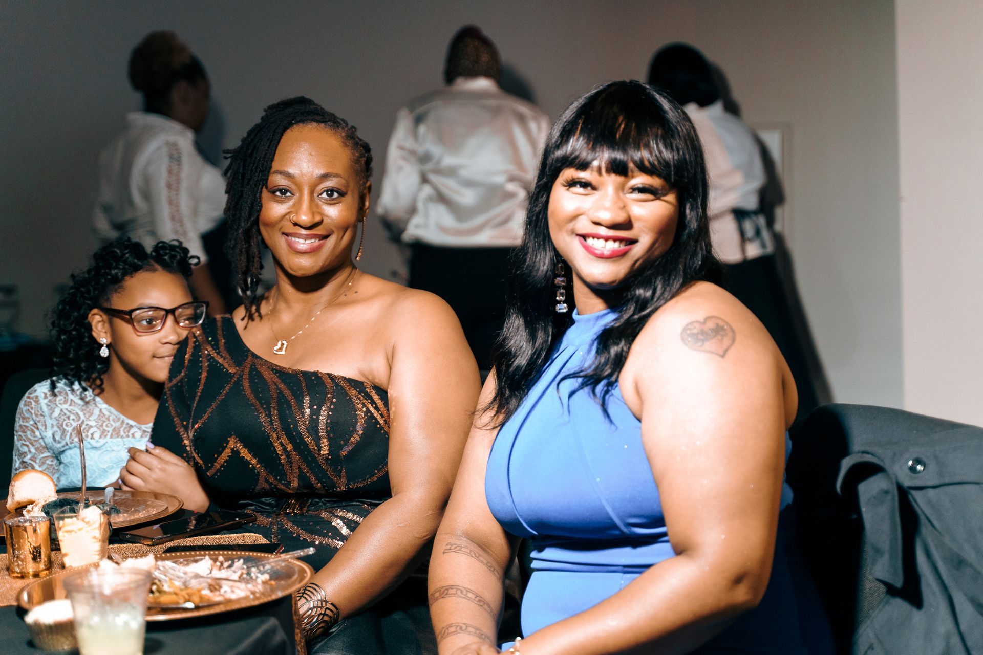 Two women are posing for a picture while sitting at a table.