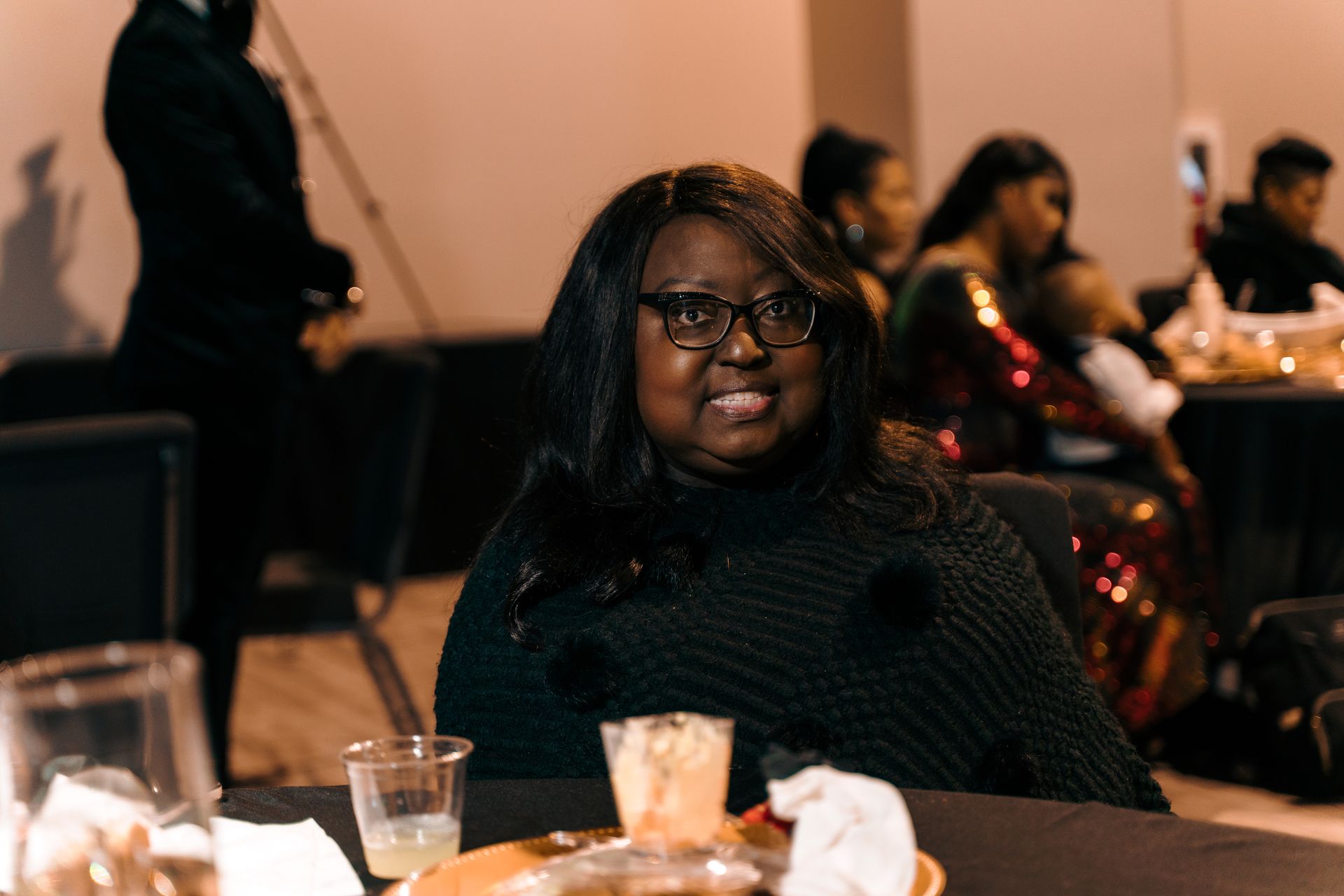 A woman wearing glasses is sitting at a table at a party.