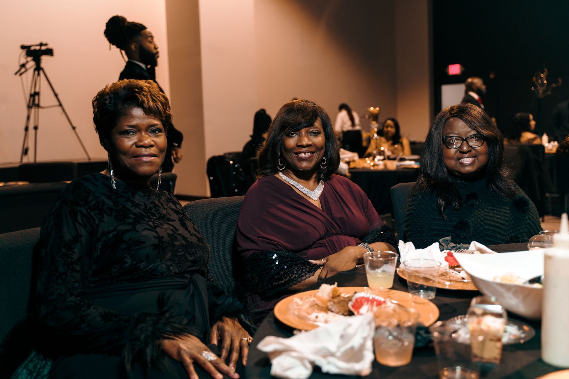 Three women are sitting at a table with plates of food.
