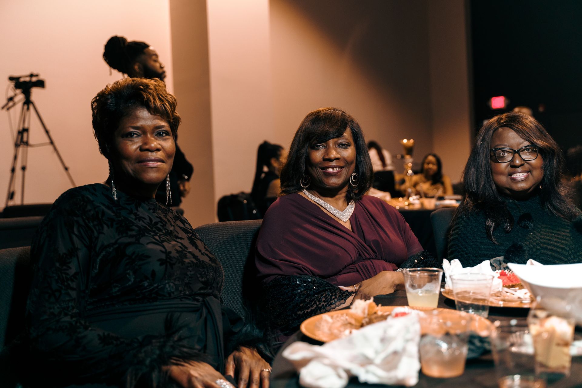 Three women are sitting at a table with plates of food.