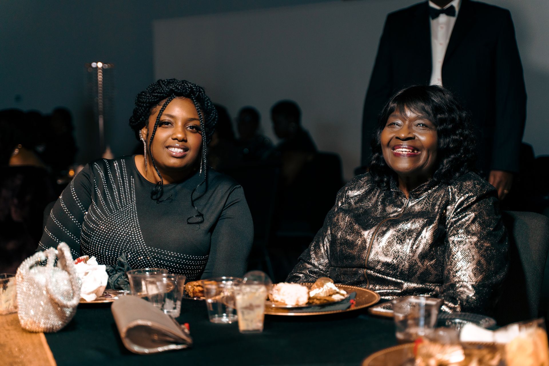 Two women are sitting at a table with plates of food.