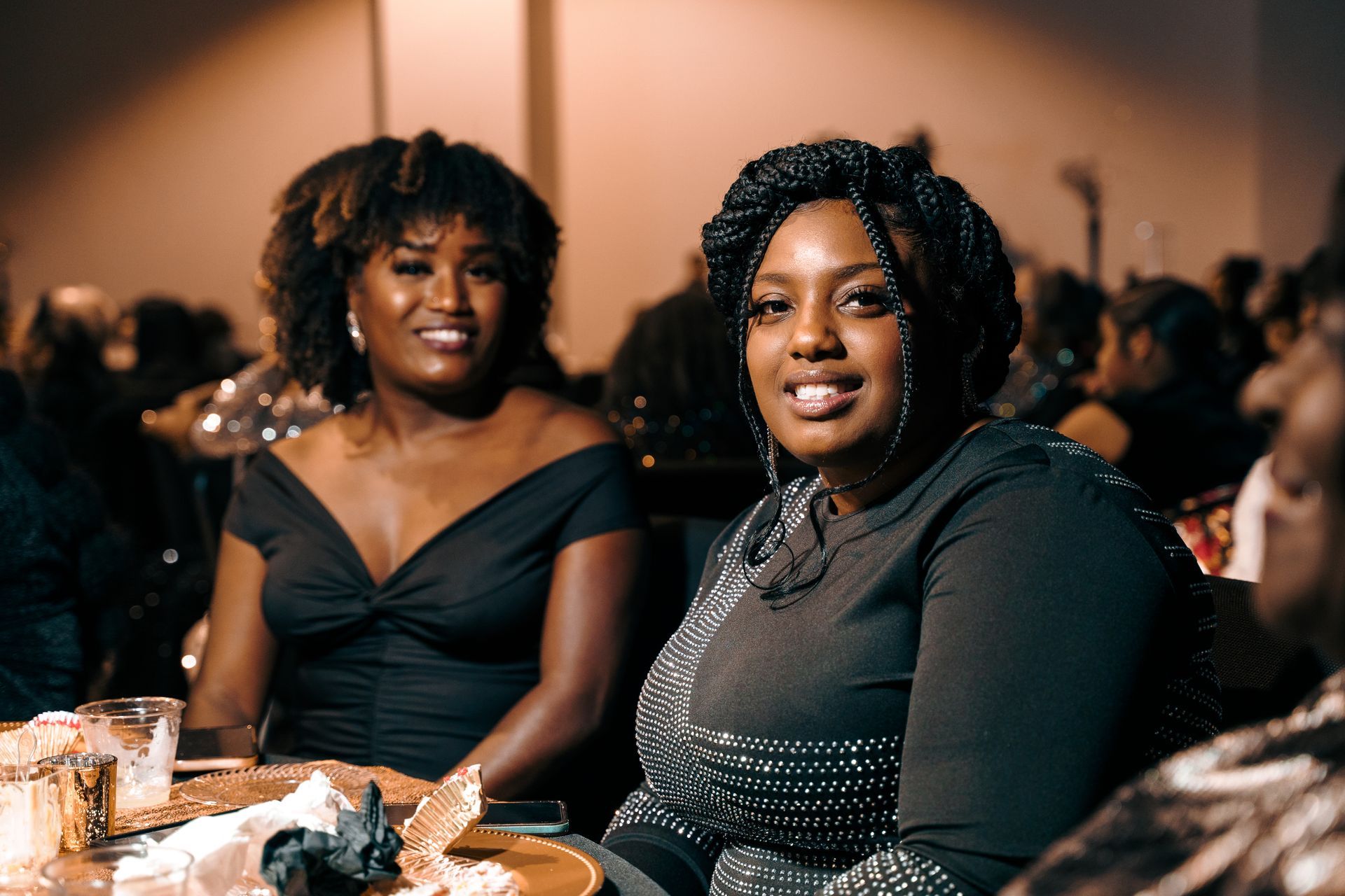 Two women are sitting at a table smiling at the camera.