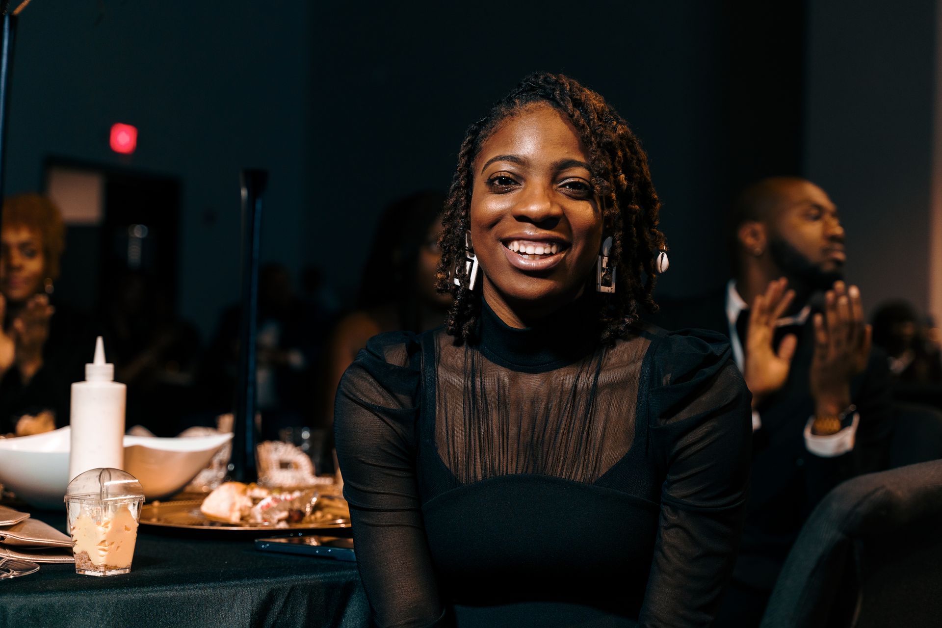 A woman is smiling while sitting at a table at a party.