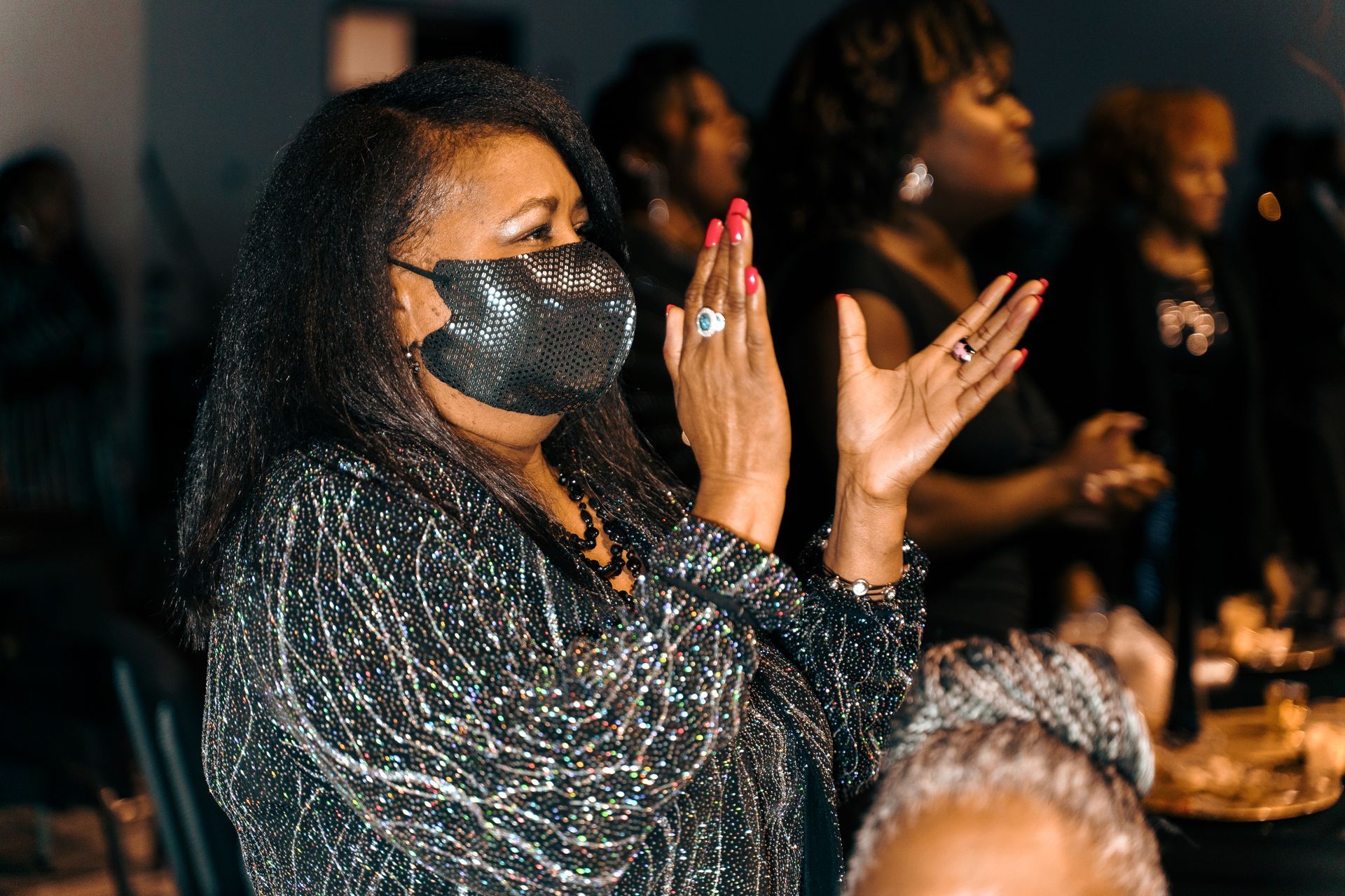 A woman wearing a mask is clapping her hands in a church.