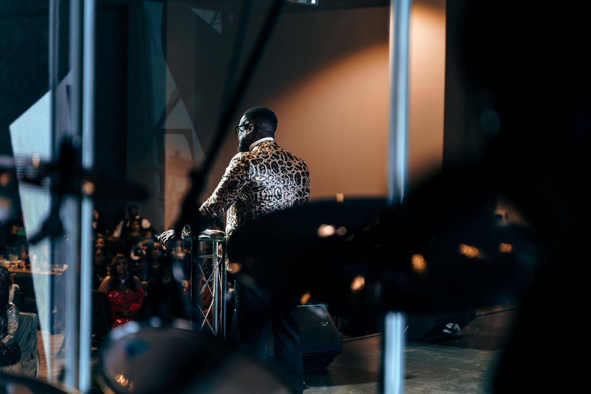 A man in a leopard print shirt is playing drums in front of a crowd.