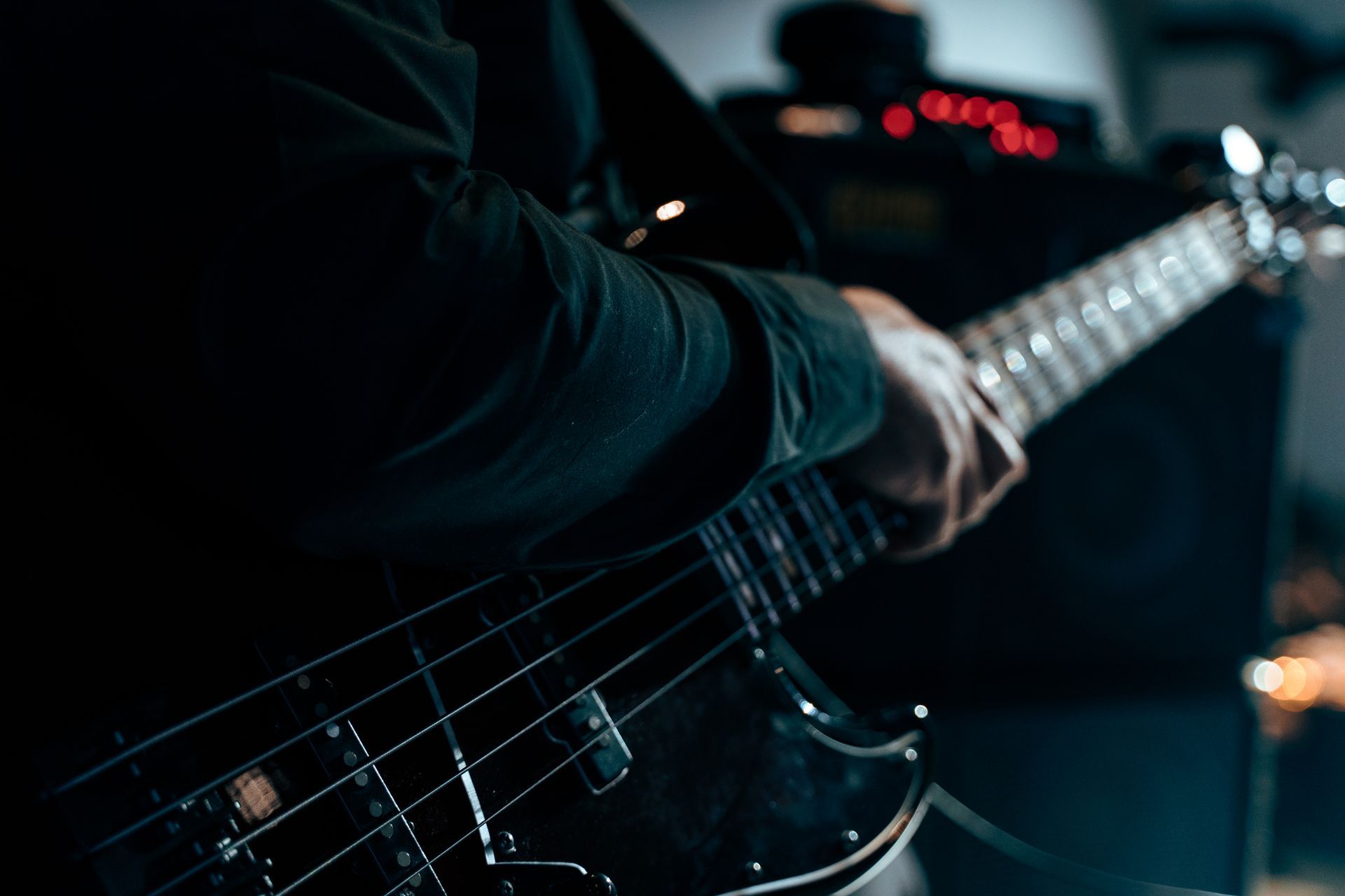 A man is playing a bass guitar in a dark room.