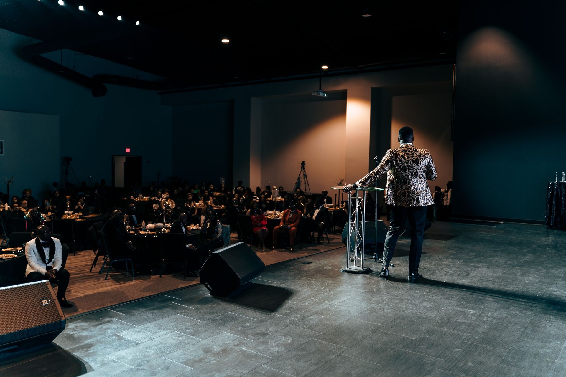 A man is standing on a stage giving a speech in front of a crowd.