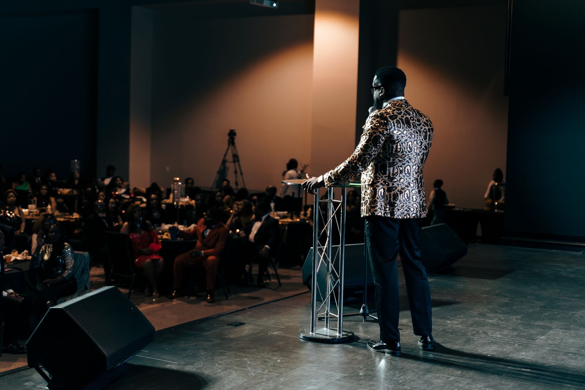 A man is standing at a podium on a stage giving a speech.