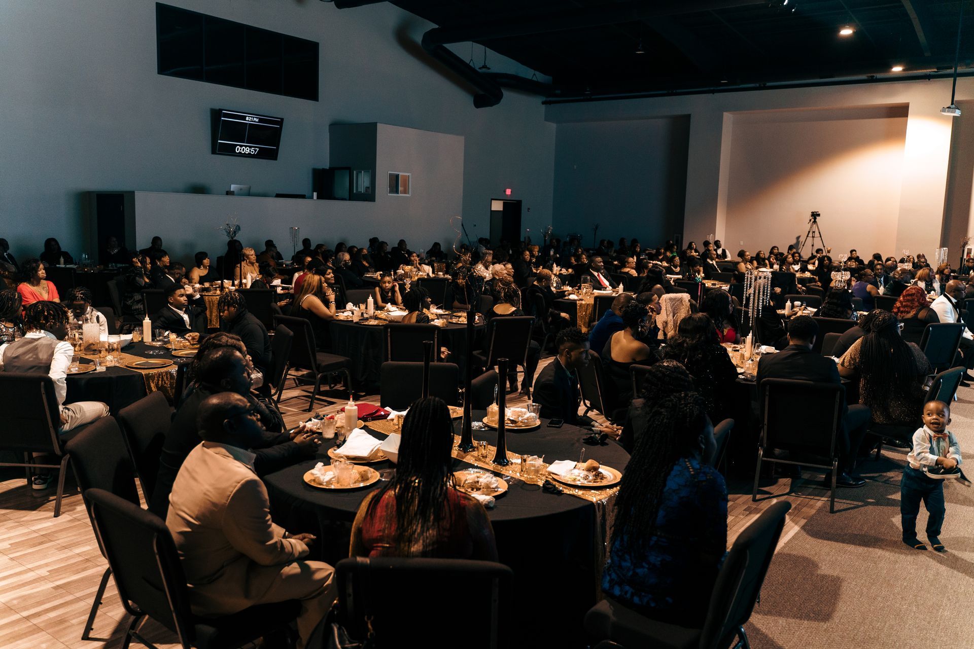 A large group of people are sitting at tables in a large room.