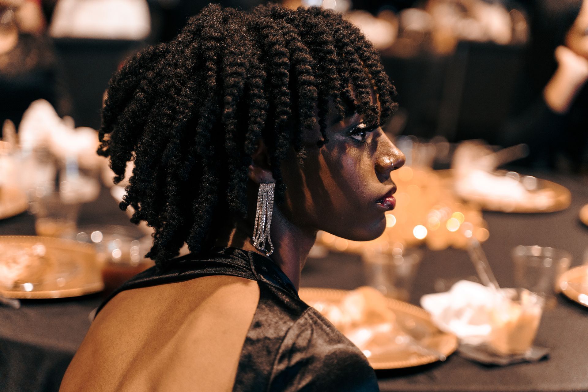 A woman in a black dress is sitting at a table with plates of food.