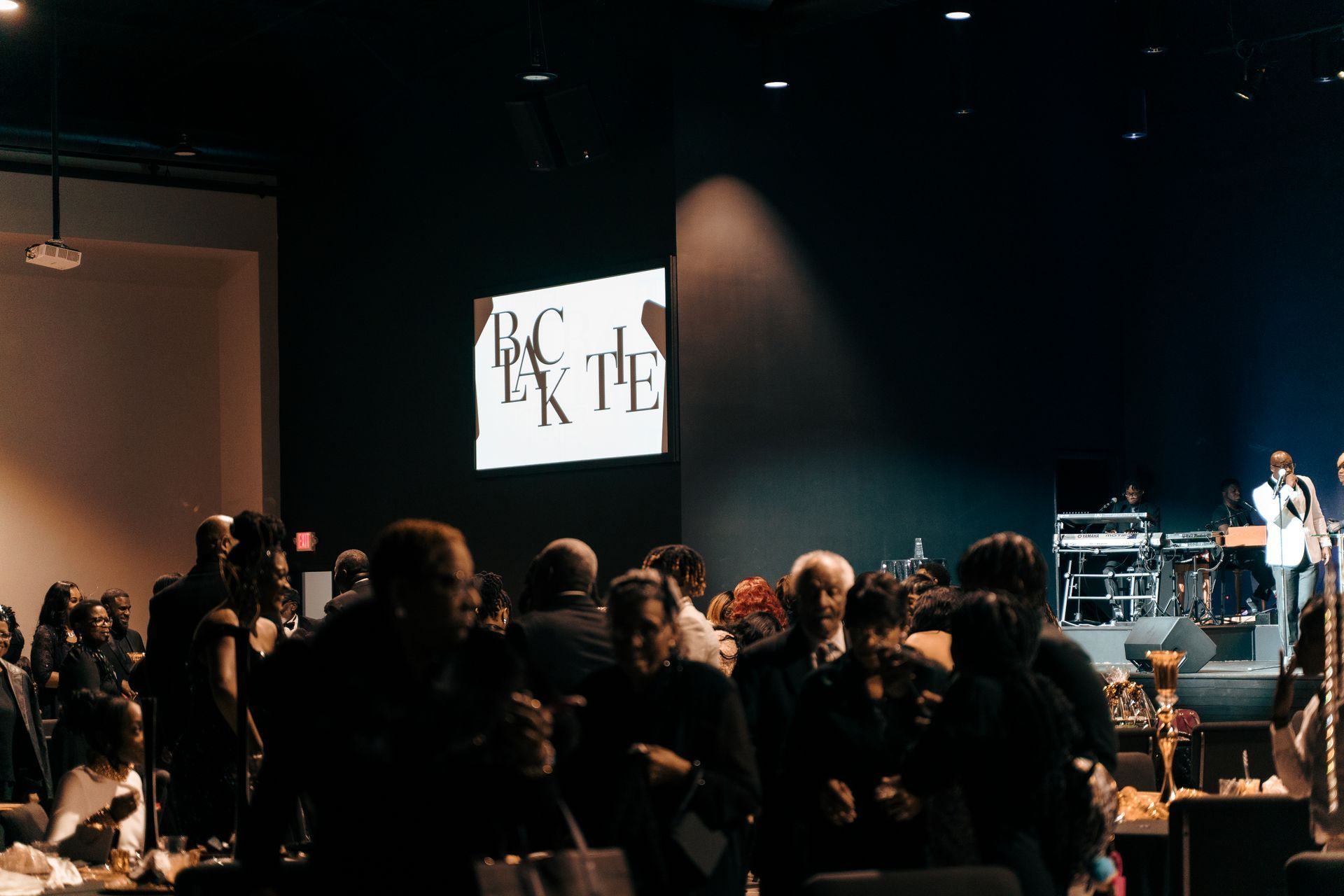 A group of people are standing in front of a large screen in a dark room.