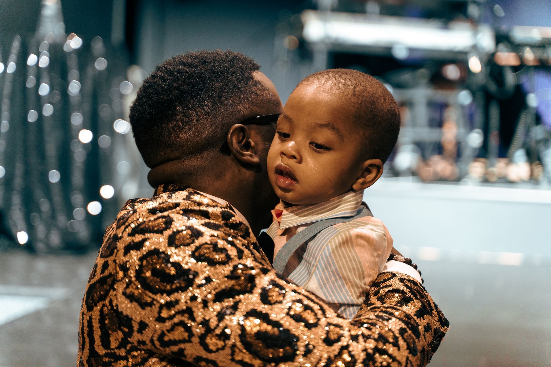 A man is holding a baby in his arms and kissing it on the cheek.