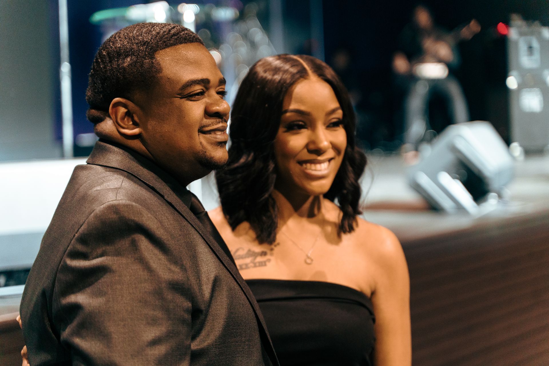 A man and a woman are posing for a picture on a stage.