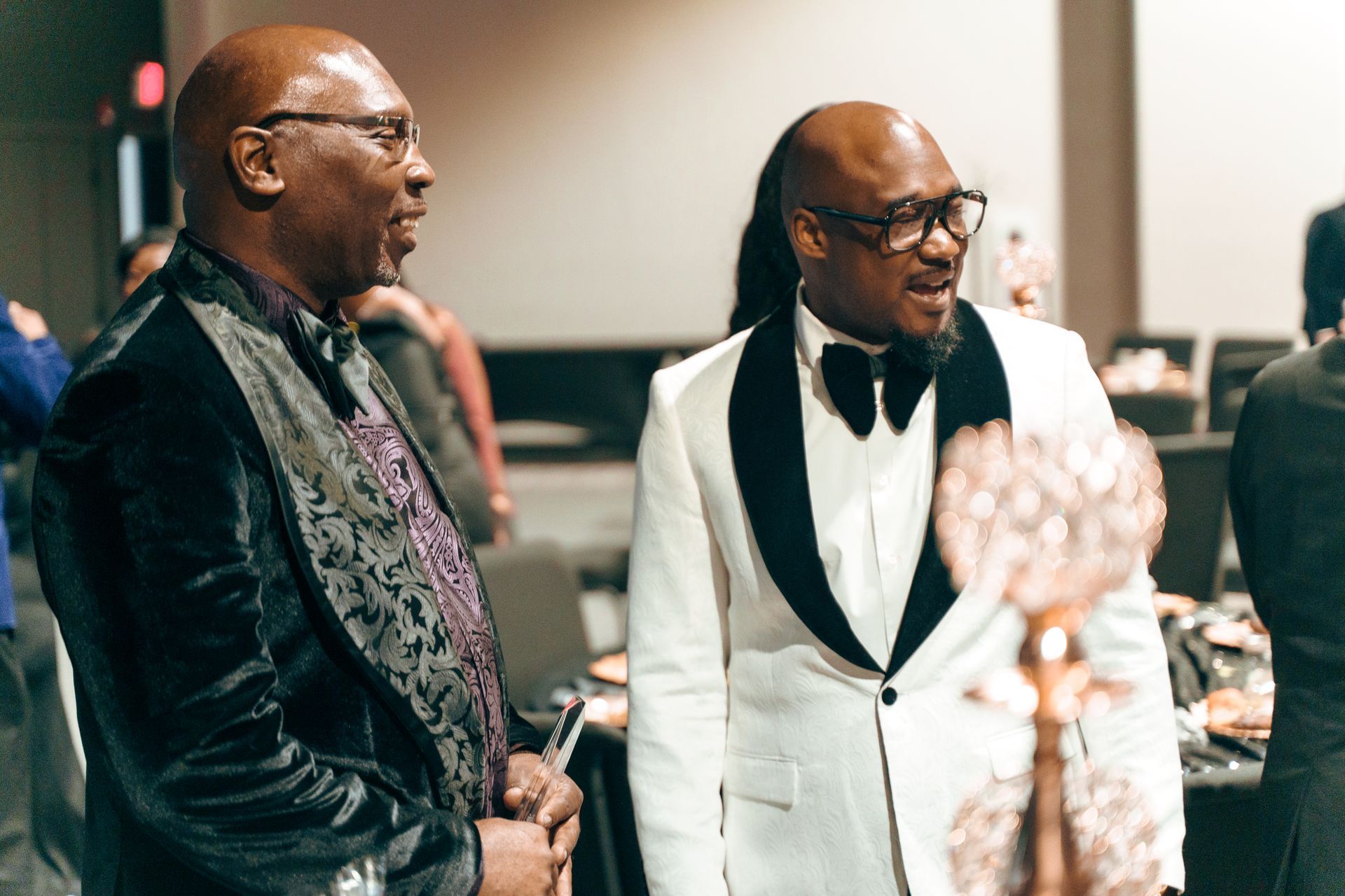 Two men in tuxedos are standing next to each other in a room.