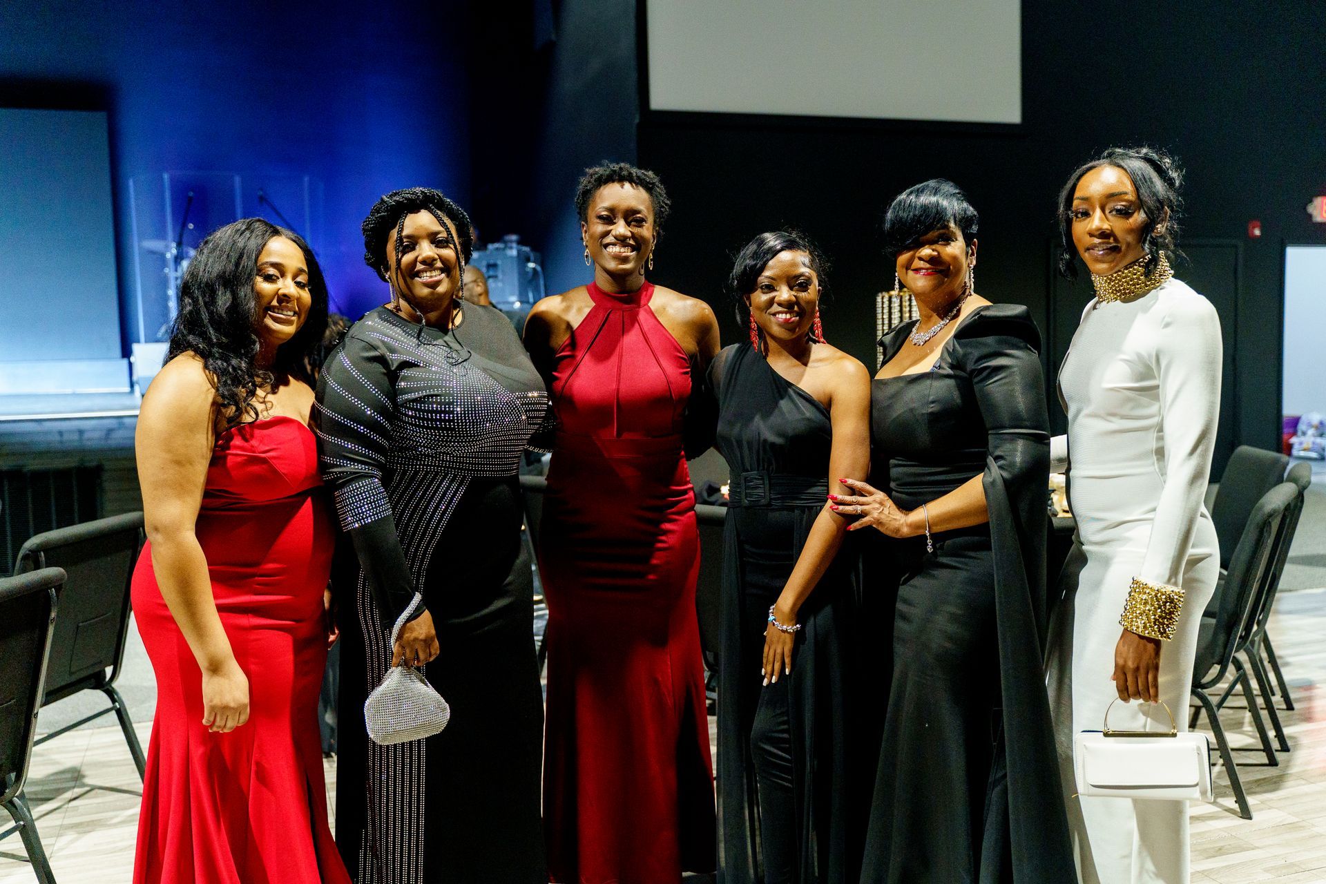 A group of women in red and black dresses are posing for a picture.