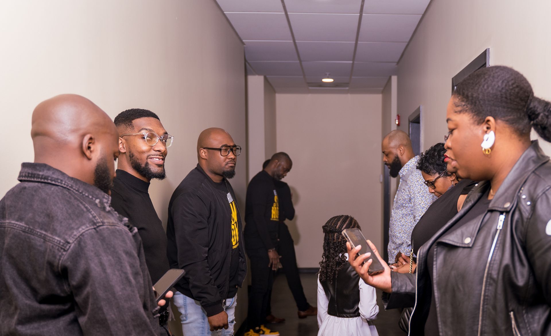 A group of people are standing in a hallway talking to each other.