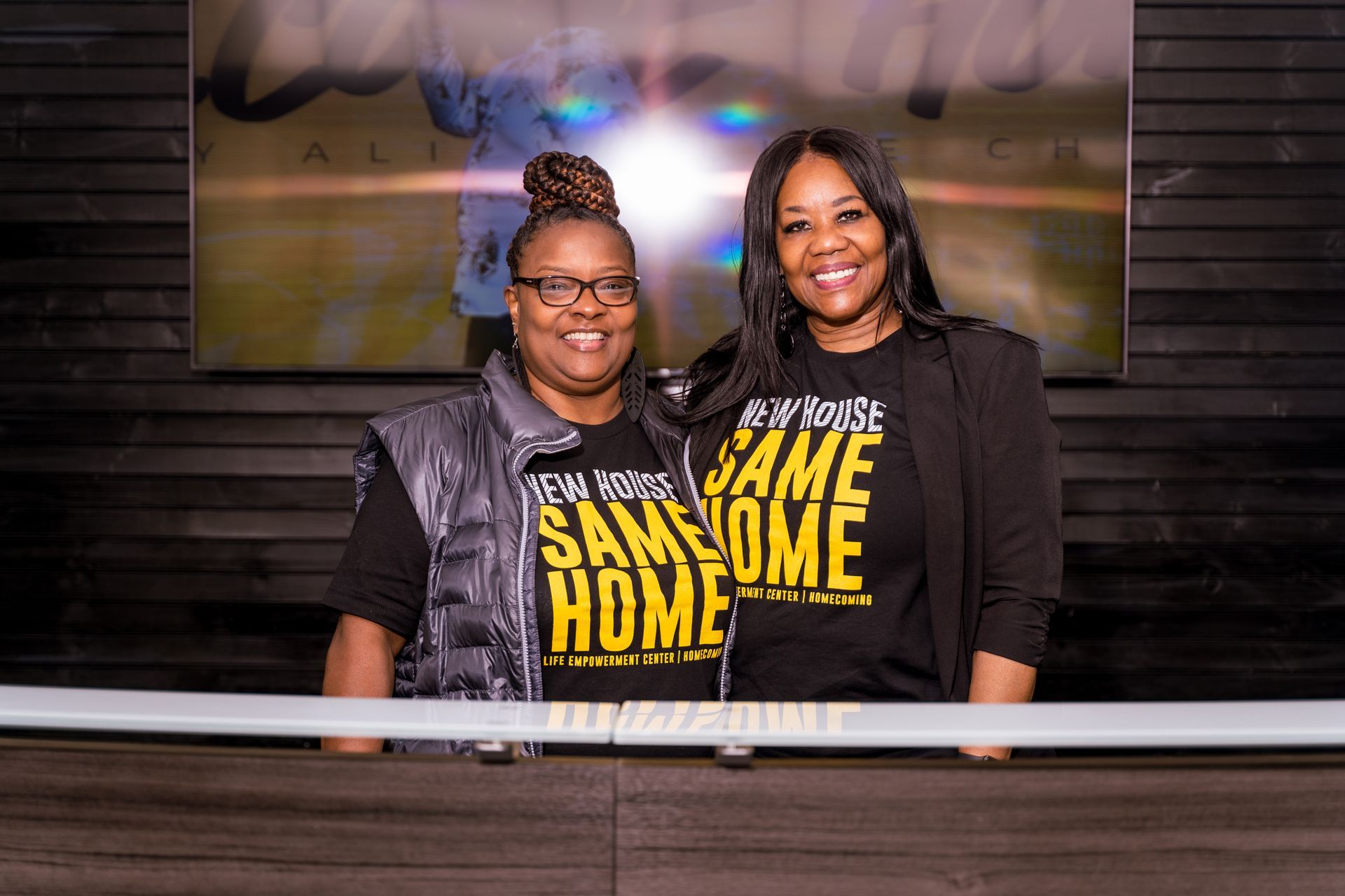 Two women wearing same home shirts are standing next to each other.