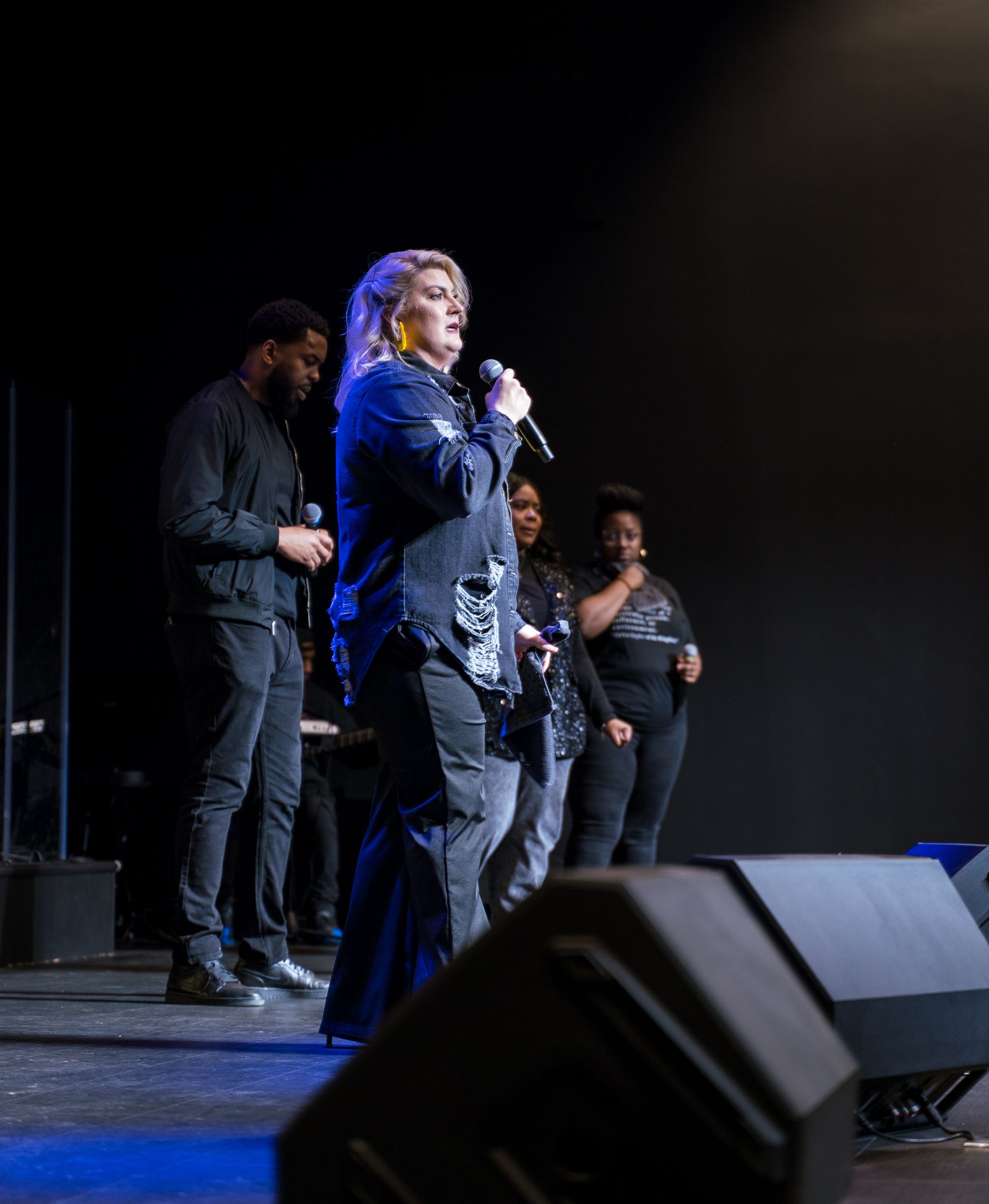 A woman is singing into a microphone on a stage.